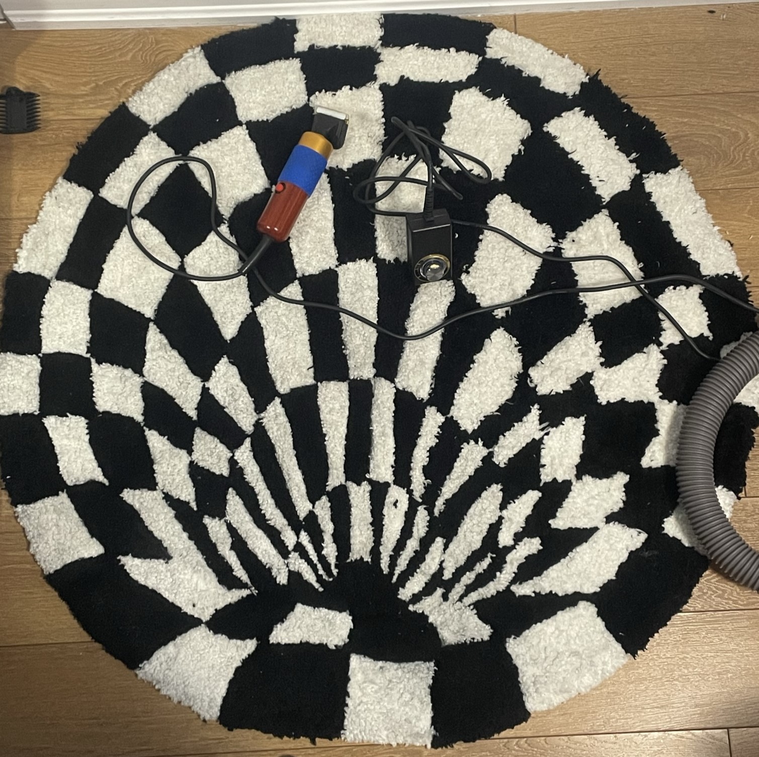 After the carpet is tufted, glued and dried, it is time to use animal trimmers to shave the yarn edges for a clearer effect. Shortening the fibres where the colours meet one another prevents them from mixing and blurring the desired illusion, which was to be a vortex tunnelling down from my hallway floor